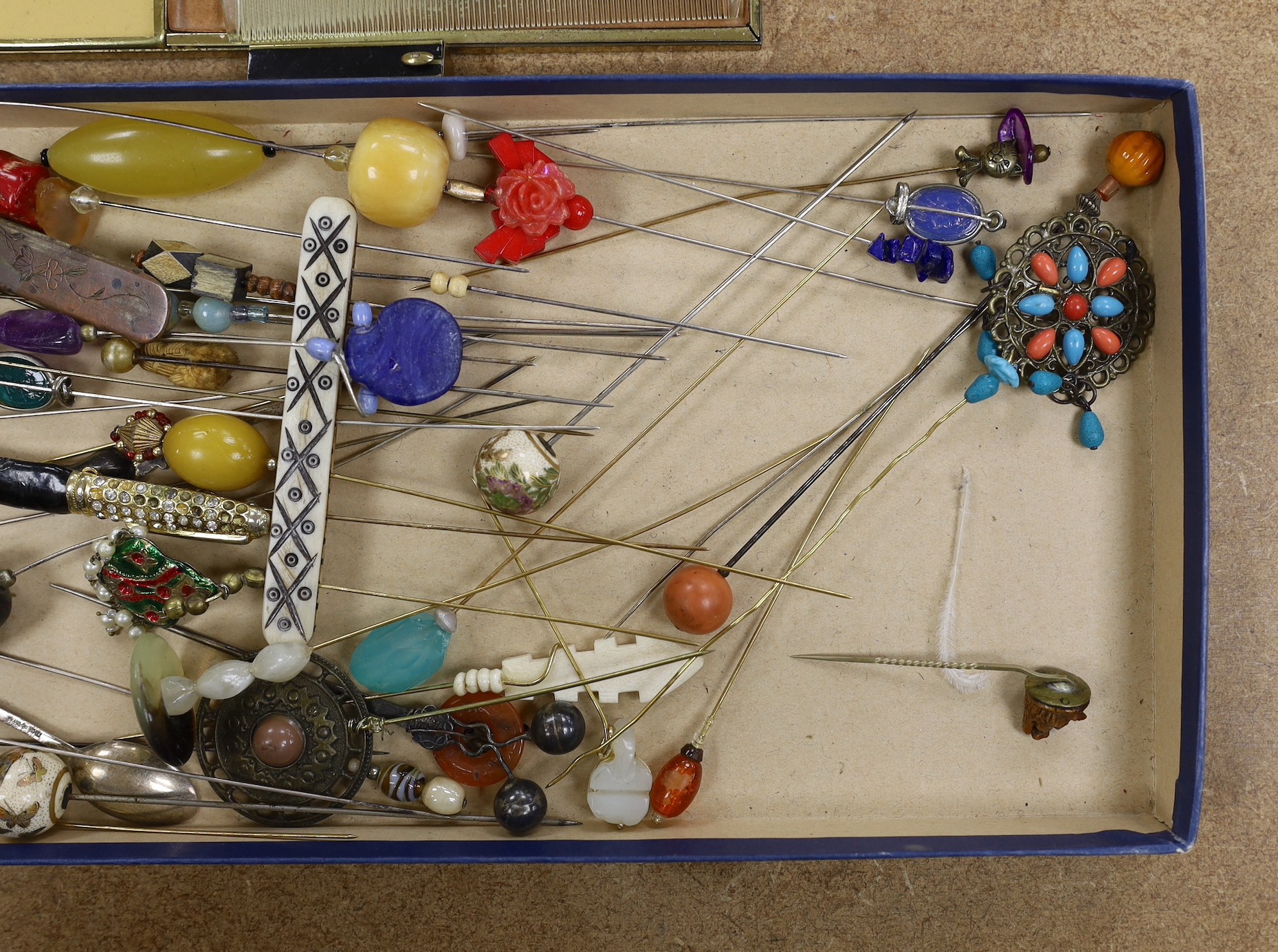 A collection of hat pins and a large enamel compact